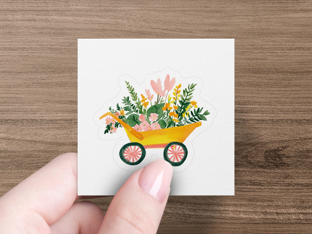Yellow wheelbarrow sticker overflowing with colorful flowers and greenery.