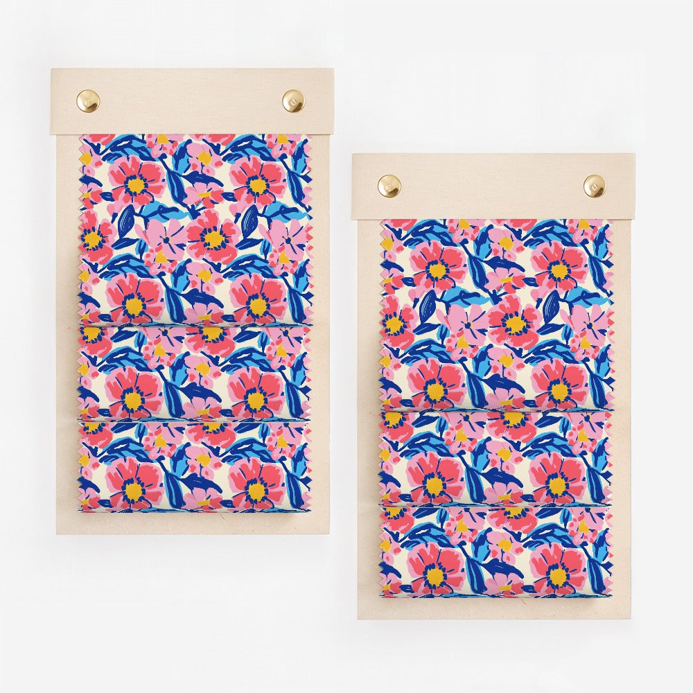 Two fabric swatches with a colorful floral pattern on wooden boards.