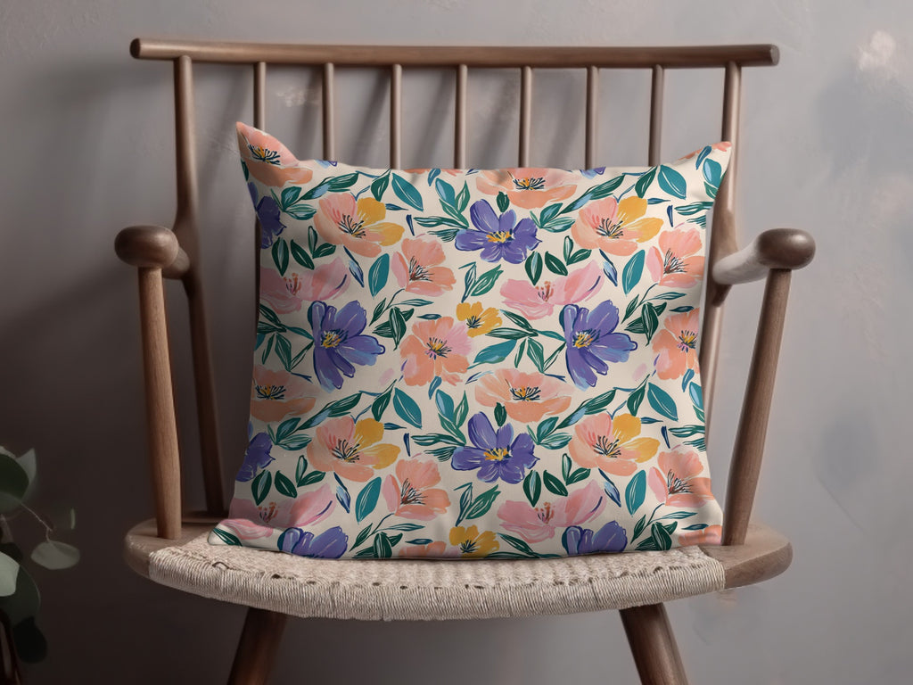 Beige pillow with a colorful floral watercolor pattern in pink, purple, and yellow.