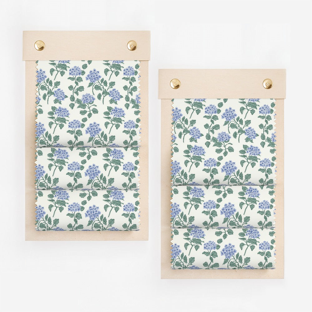 Floral fabric samples on wooden swatch boards, light blue flowers on white.