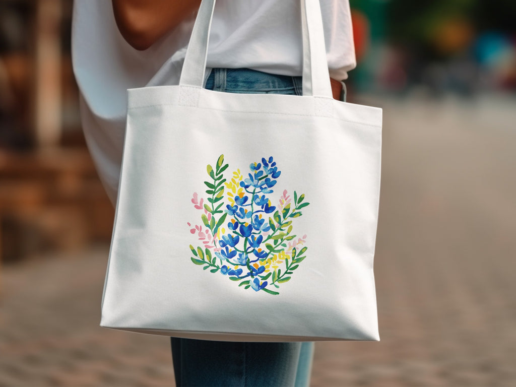 White tote bag with a watercolor floral design of bluebonnets and yellow flowers.