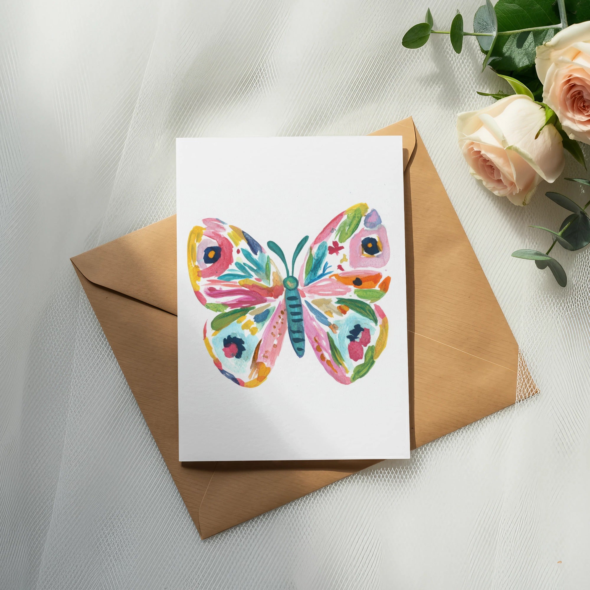 Watercolor butterfly card on a brown envelope with roses and eucalyptus.
