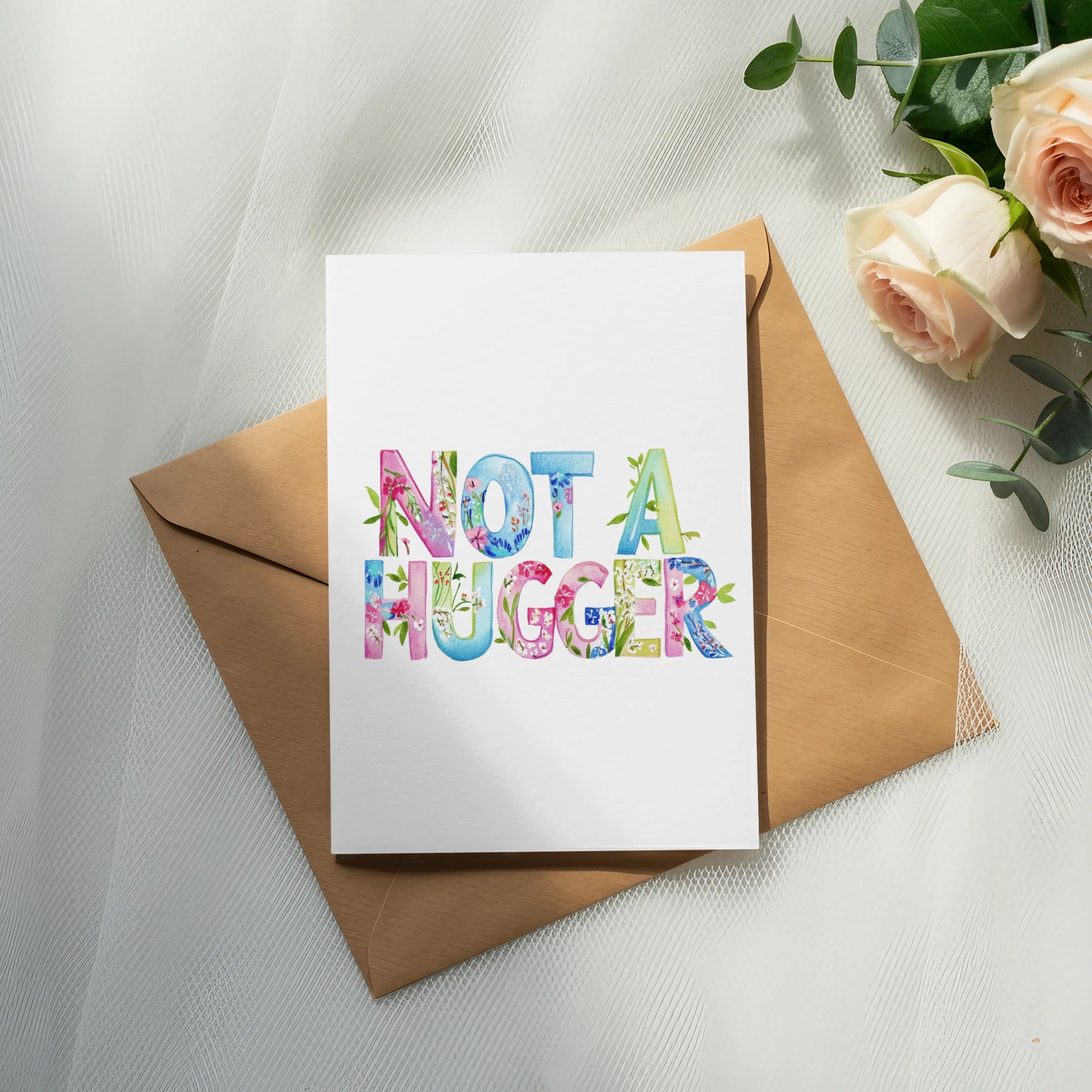 Greeting card with "Not A Hugger" text, surrounded by roses and eucalyptus.