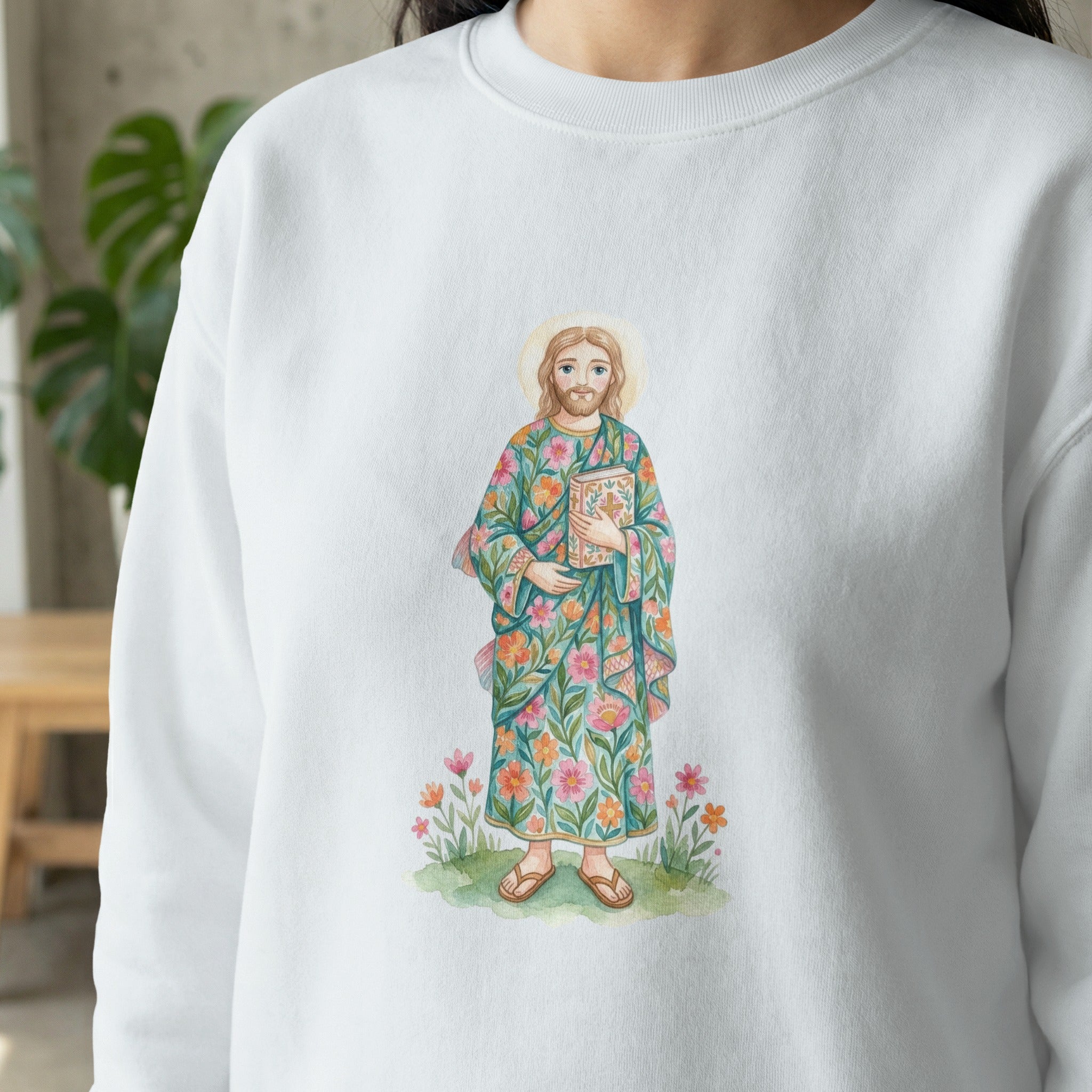 Jesus in a floral robe holds a book, standing on grass with flowers.