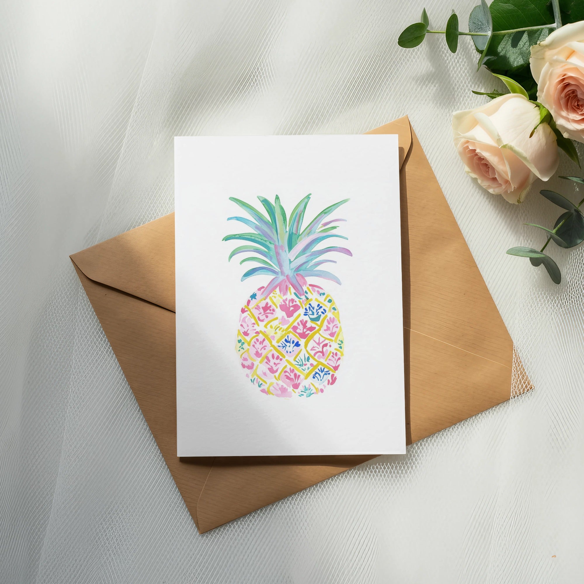 Watercolor pineapple illustration on white card with brown envelope and roses.