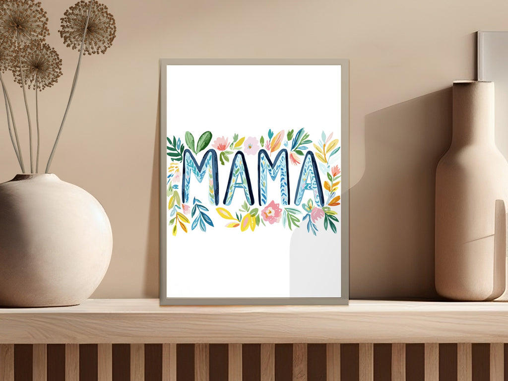 Floral "MAMA" text art in a white frame on a shelf.
