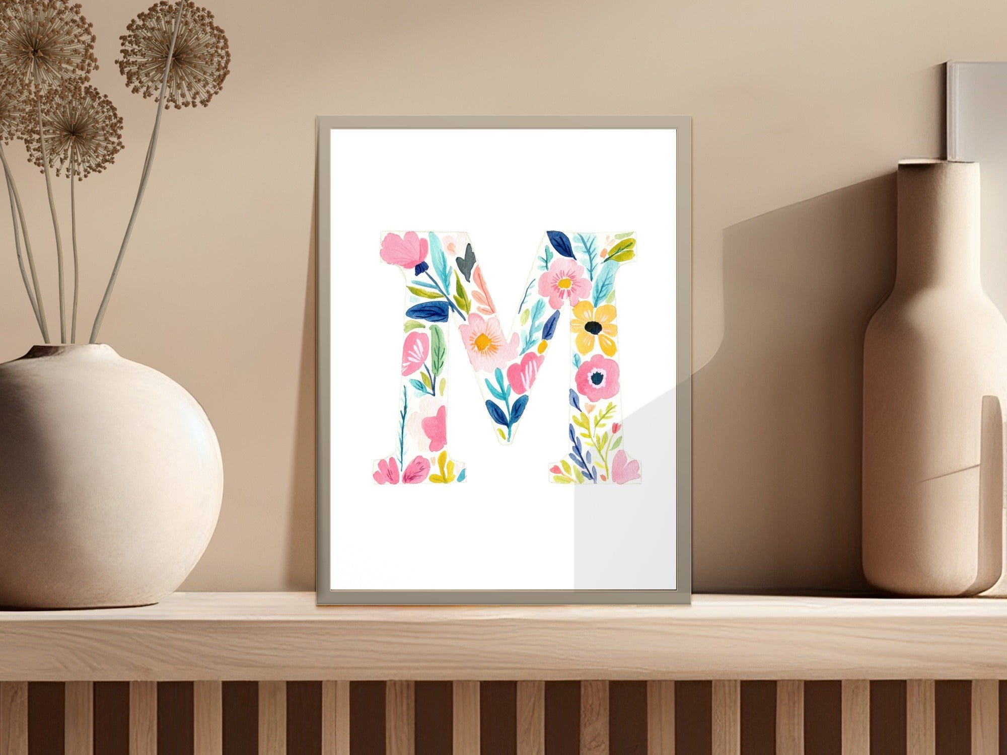 Floral letter M art print on a shelf with vases.