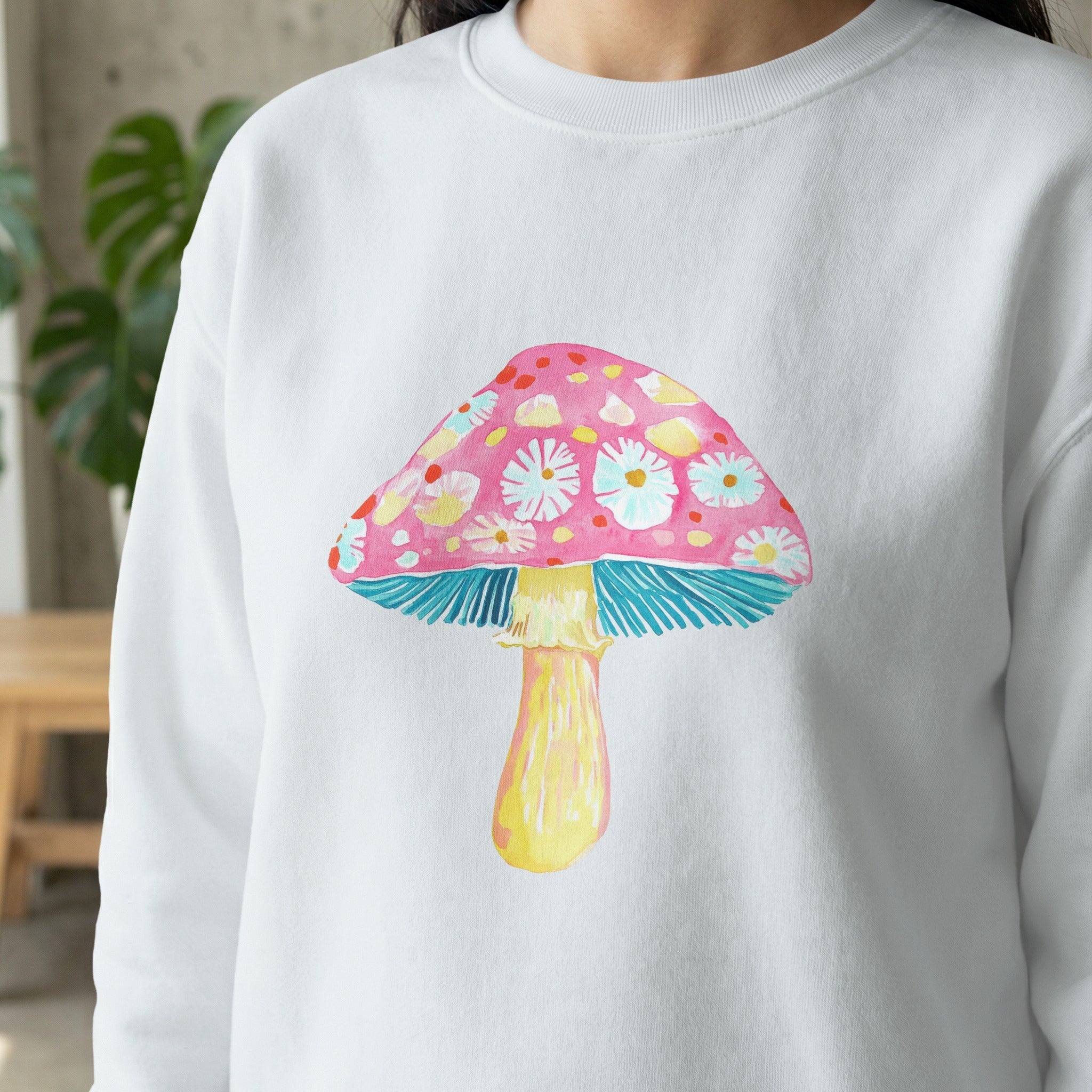 White sweatshirt with a watercolor mushroom graphic featuring pink cap and yellow stem.