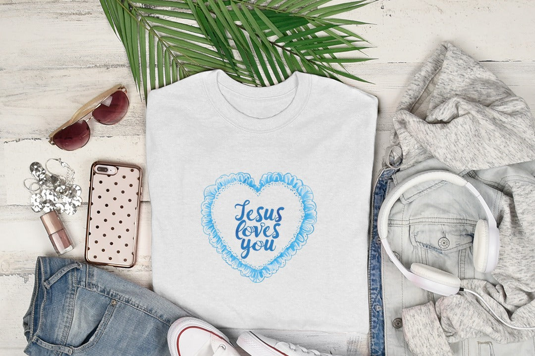 White t-shirt with "Jesus loves you" heart design, laid flat with accessories.