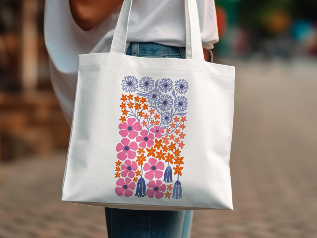 White canvas tote bag with a stylized floral pattern in pink, orange, and blue.