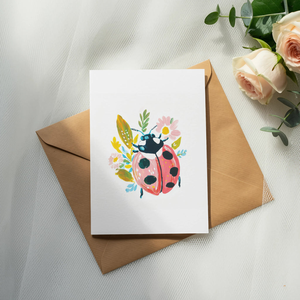 Greeting card with ladybug and floral illustration on a kraft paper envelope.