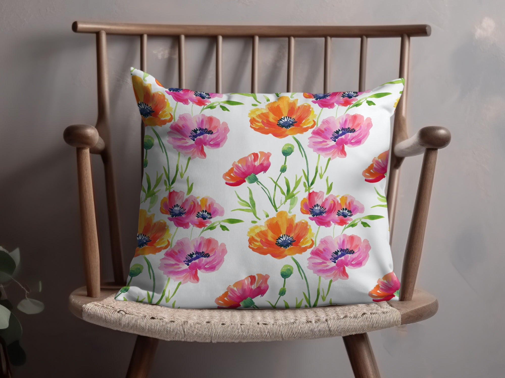 White throw pillow with a watercolor floral pattern of pink and orange poppies.