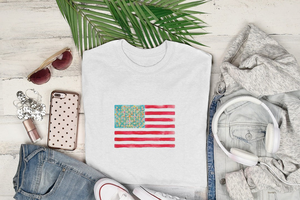 White t-shirt with watercolor American flag design and surrounding clothing.