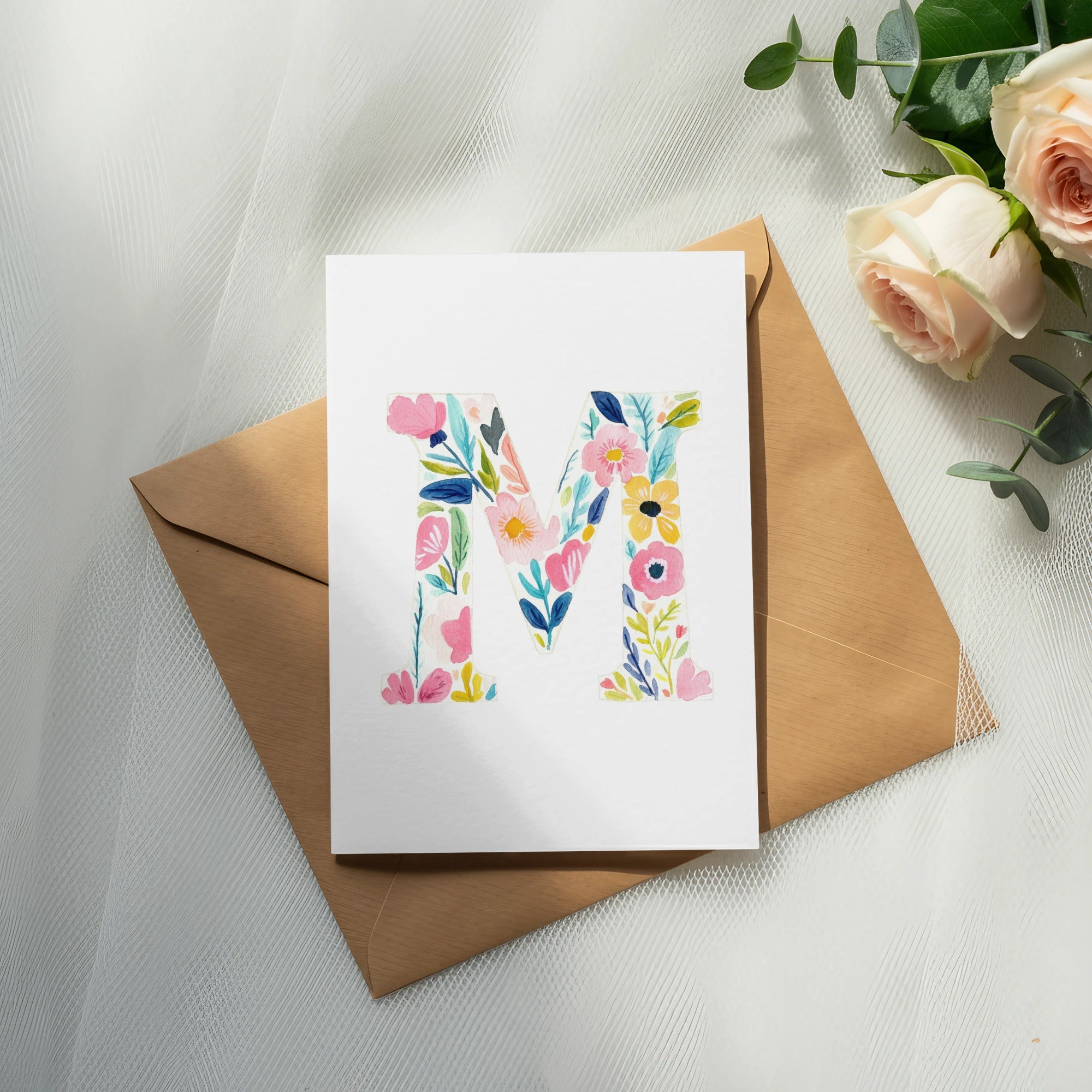 Floral letter "M" on card with envelope and roses.