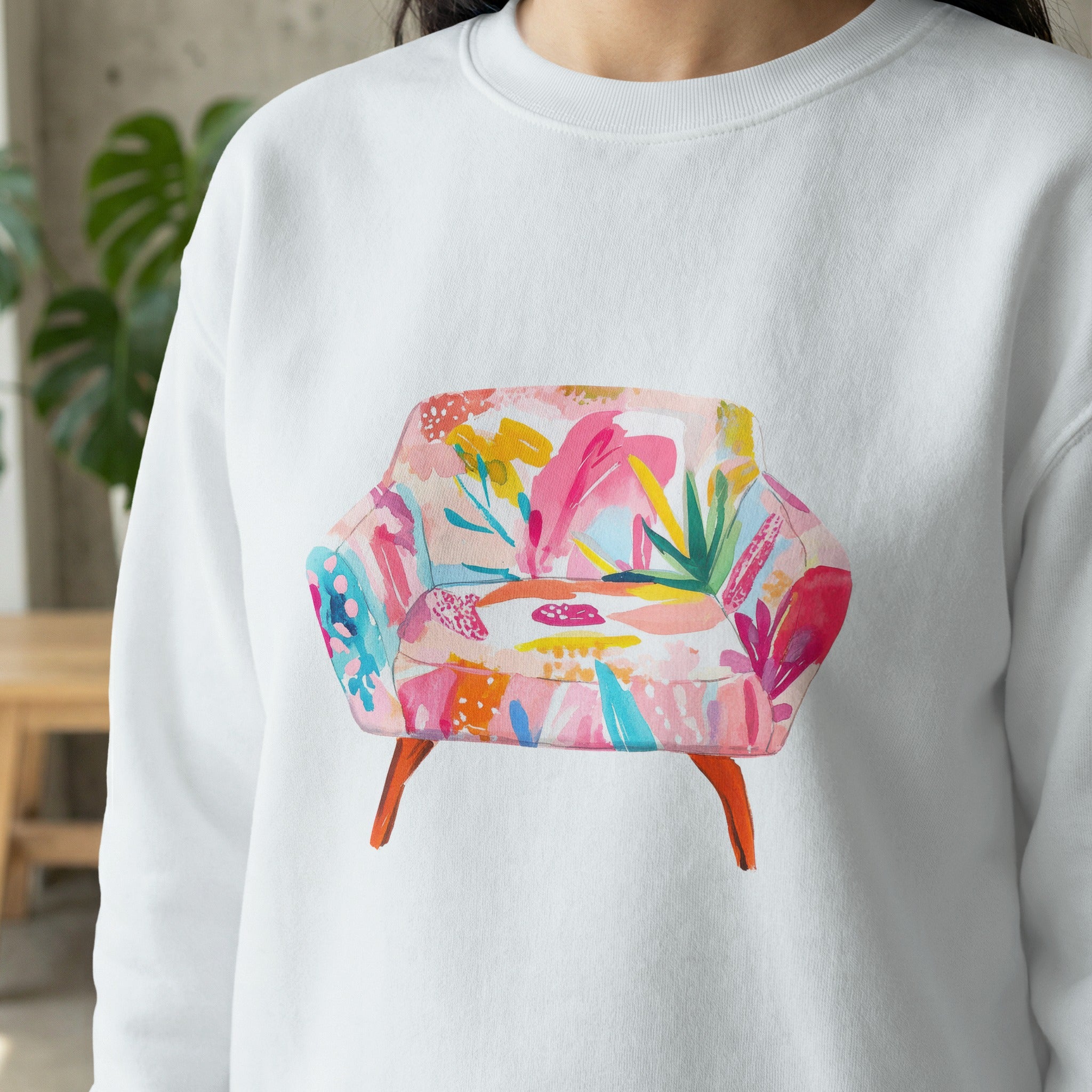 White sweatshirt with a colorful abstract floral armchair graphic.