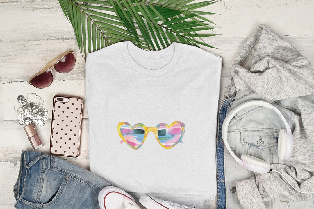 White t-shirt with colorful heart-shaped sunglasses graphic, laid flat with clothing.