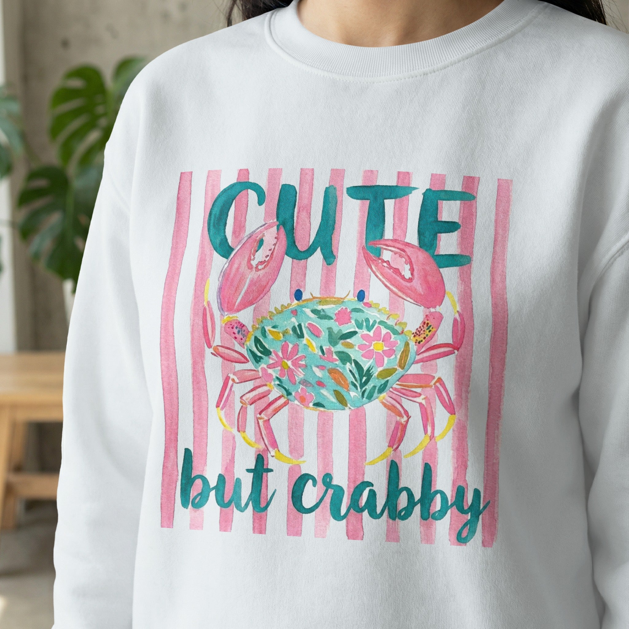 Sweatshirt with a crab graphic and "cute but crabby" text on pink stripes.