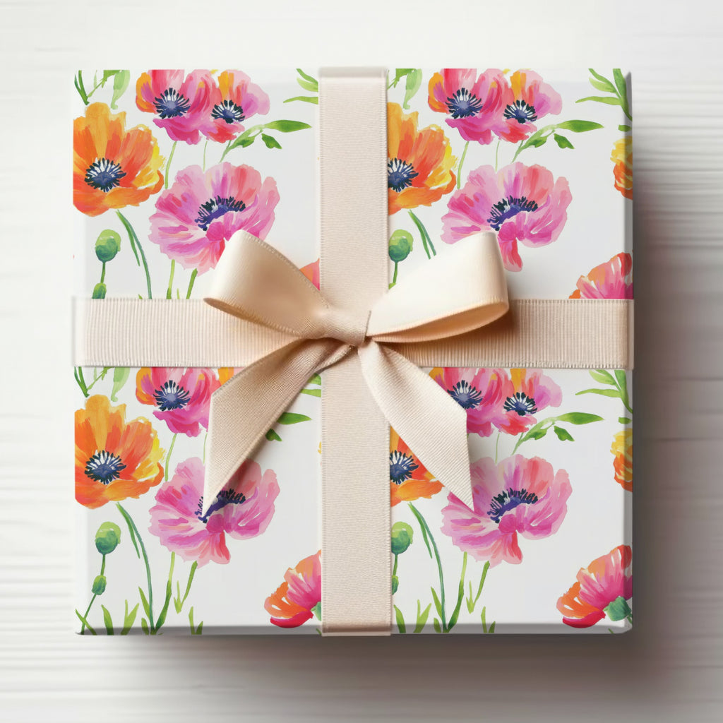Gift box wrapped in colorful poppy floral paper with a beige ribbon bow.