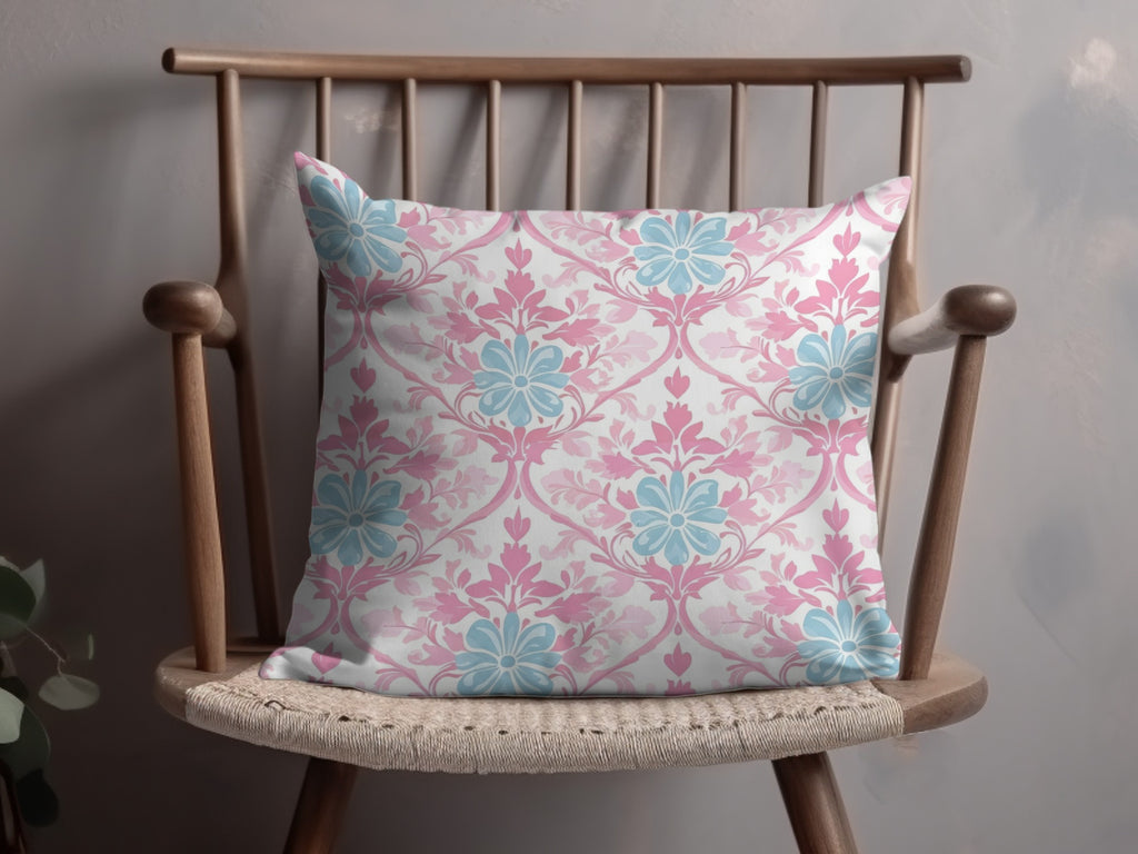 Floral damask throw pillow in pink and blue on a wooden chair.