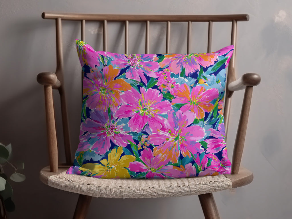 Bright floral print pillow with pink, orange, and blue flowers on a dark background.
