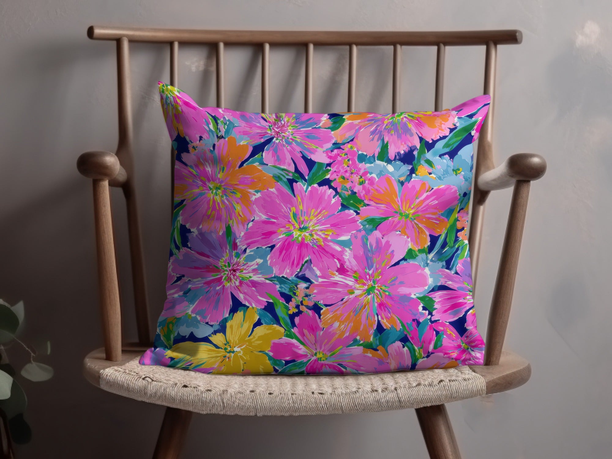Bright floral print pillow with pink, orange, and blue flowers on a dark background.