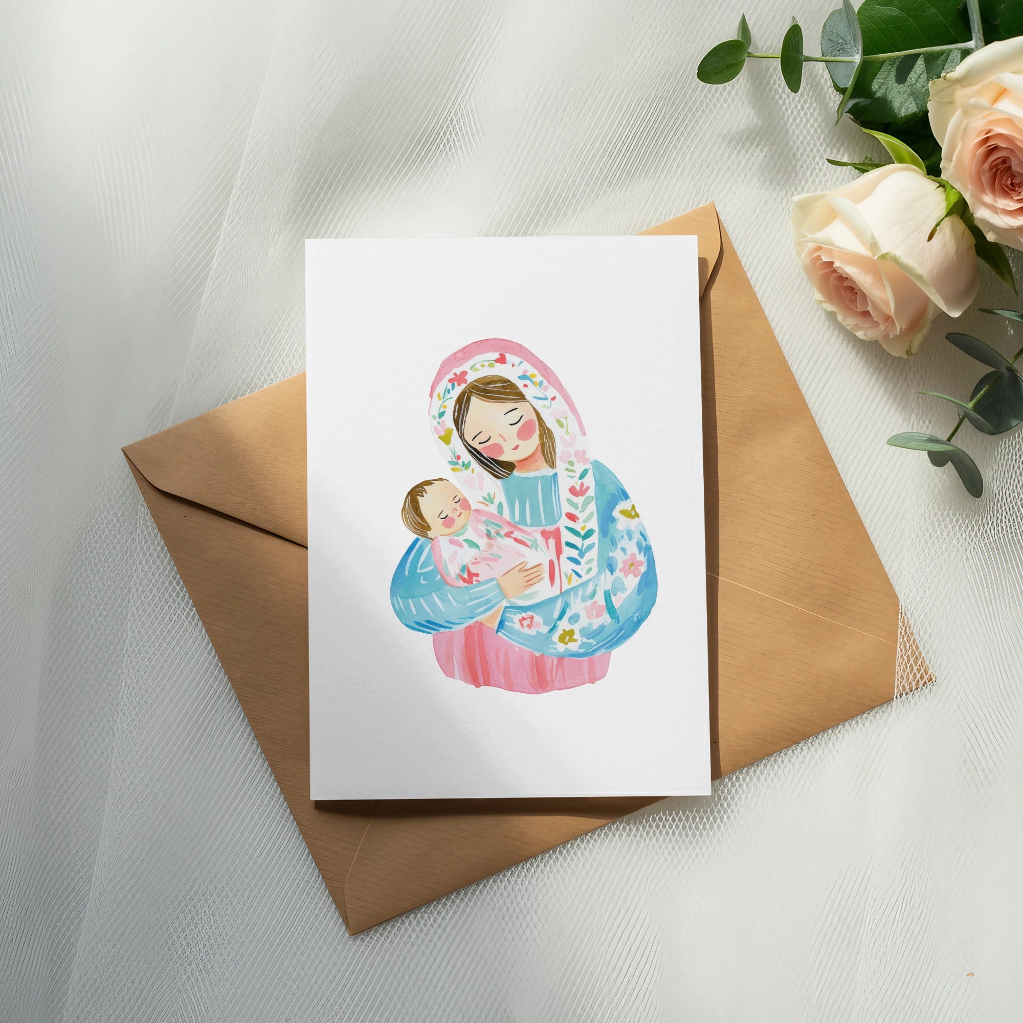 Watercolor illustration of Mary holding baby Jesus on a card, with roses and eucalyptus.