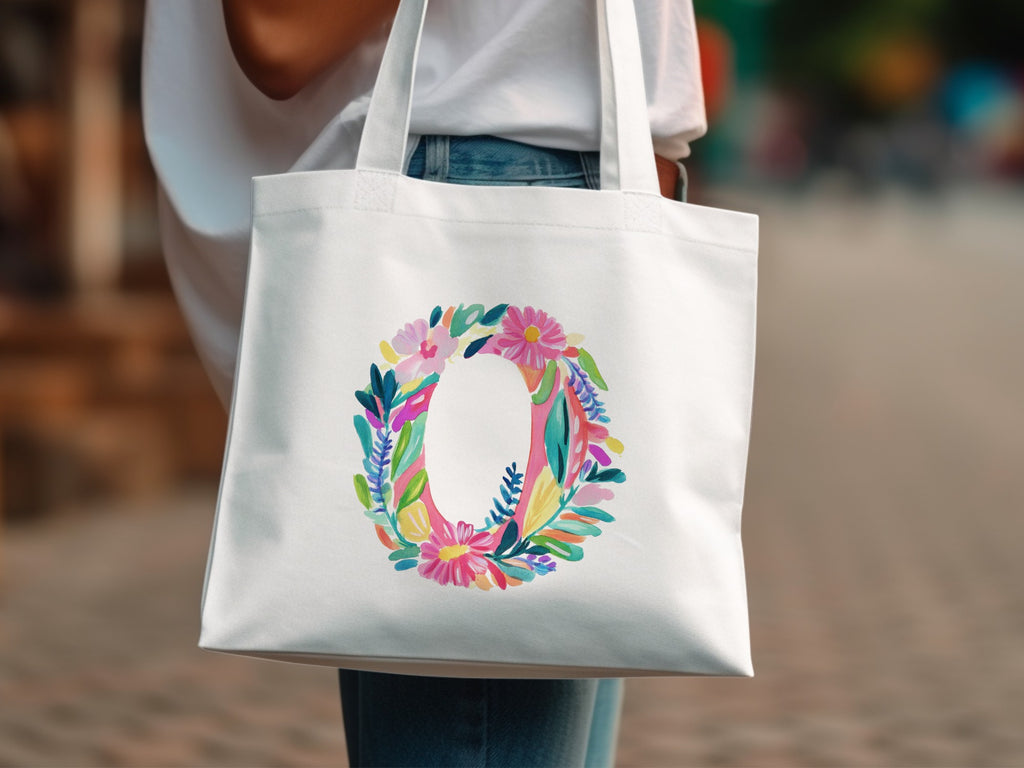 White tote bag with a colorful floral letter O design.