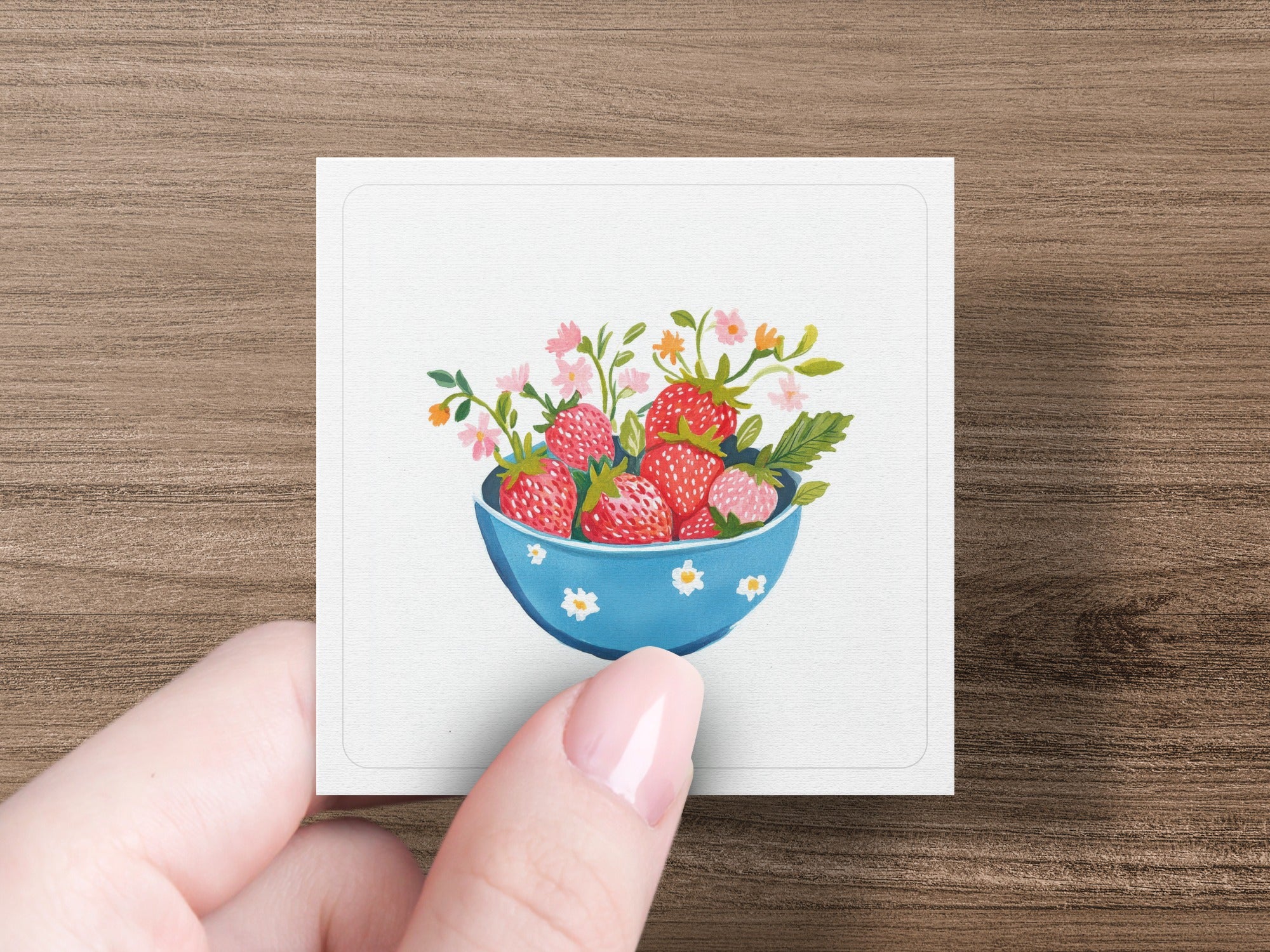 Blue bowl overflowing with strawberries and delicate pink and orange flowers.