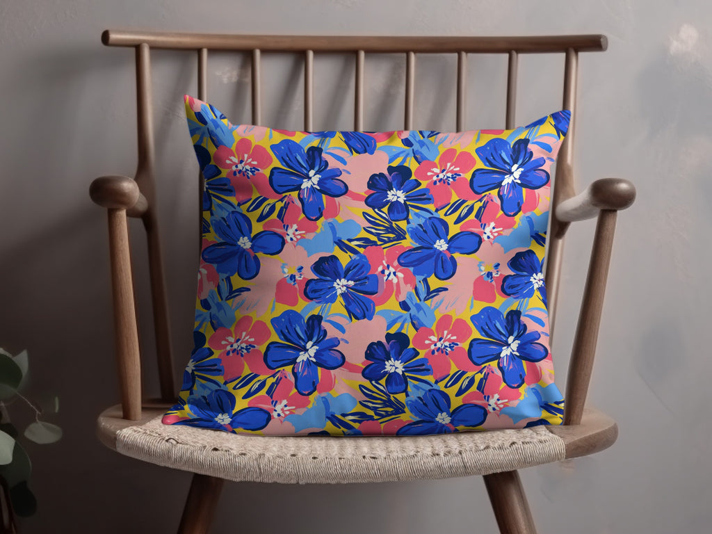 Blue and pink floral pattern on a yellow throw pillow on a wooden chair.