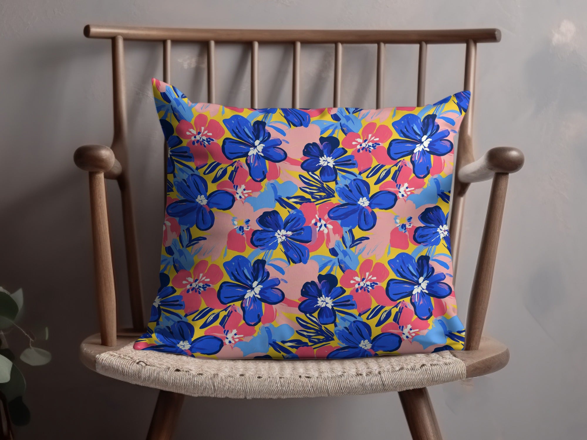 Blue and pink floral pattern on a yellow throw pillow on a wooden chair.