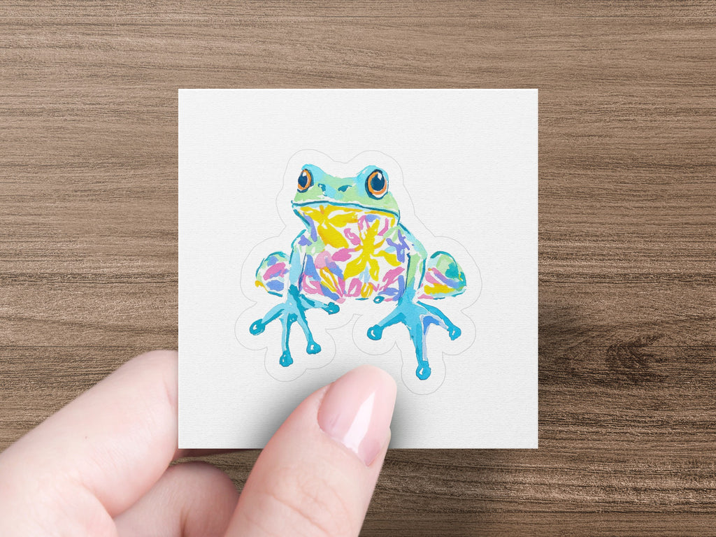 Colorful cartoon frog with big eyes on a white sticker.