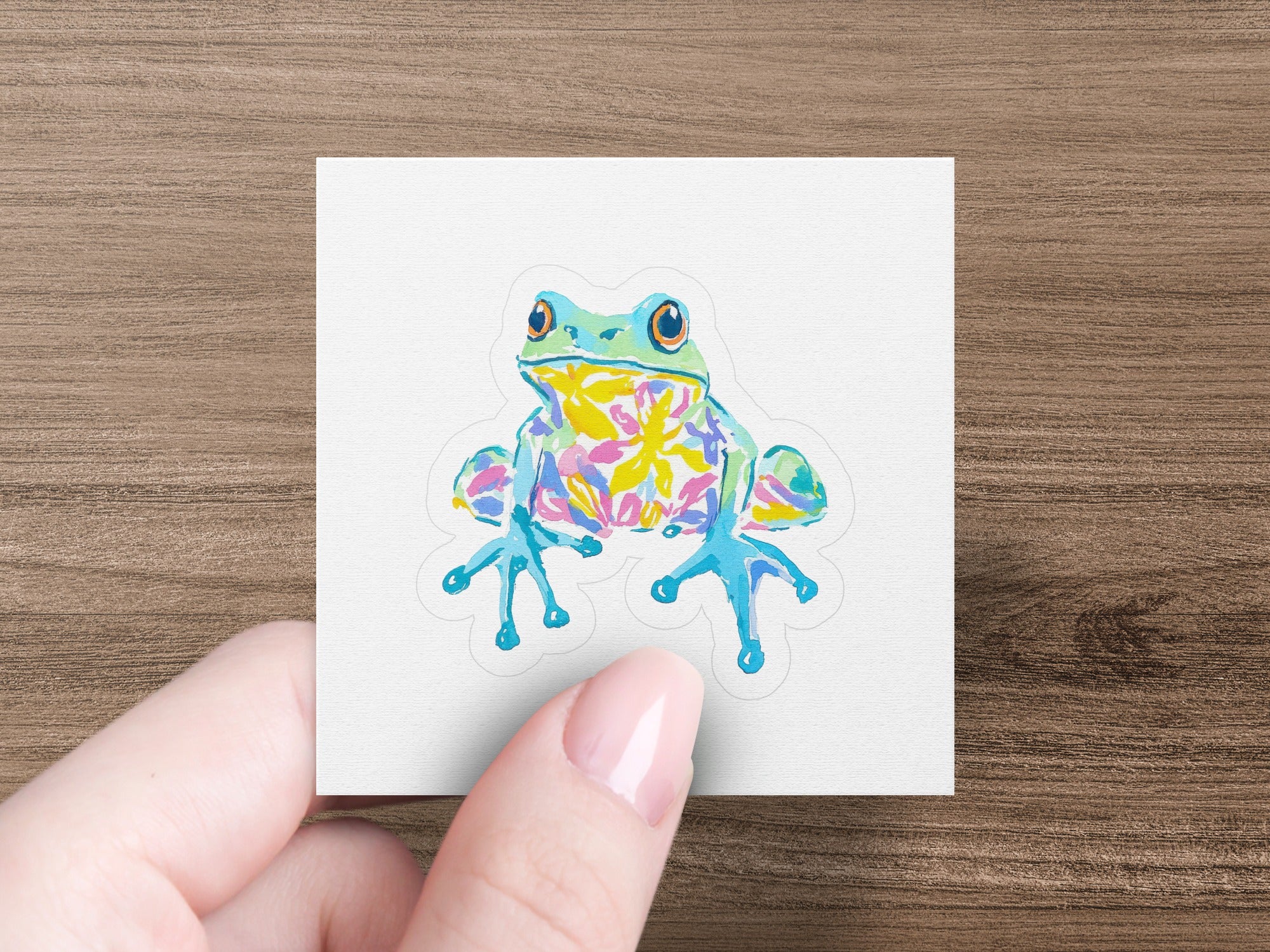 Colorful cartoon frog with big eyes on a white sticker.
