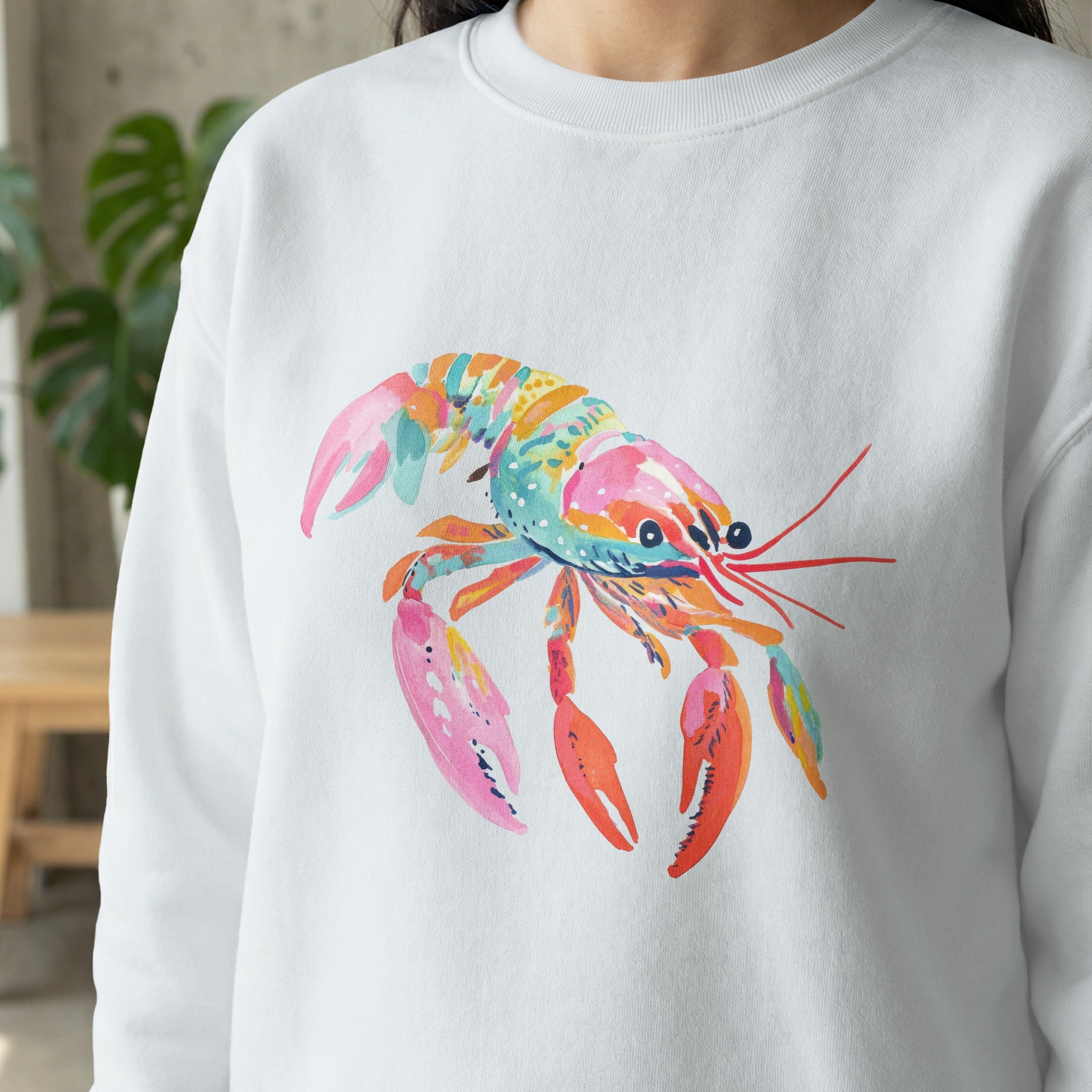 White sweatshirt featuring a vibrant, colorful watercolor lobster illustration.