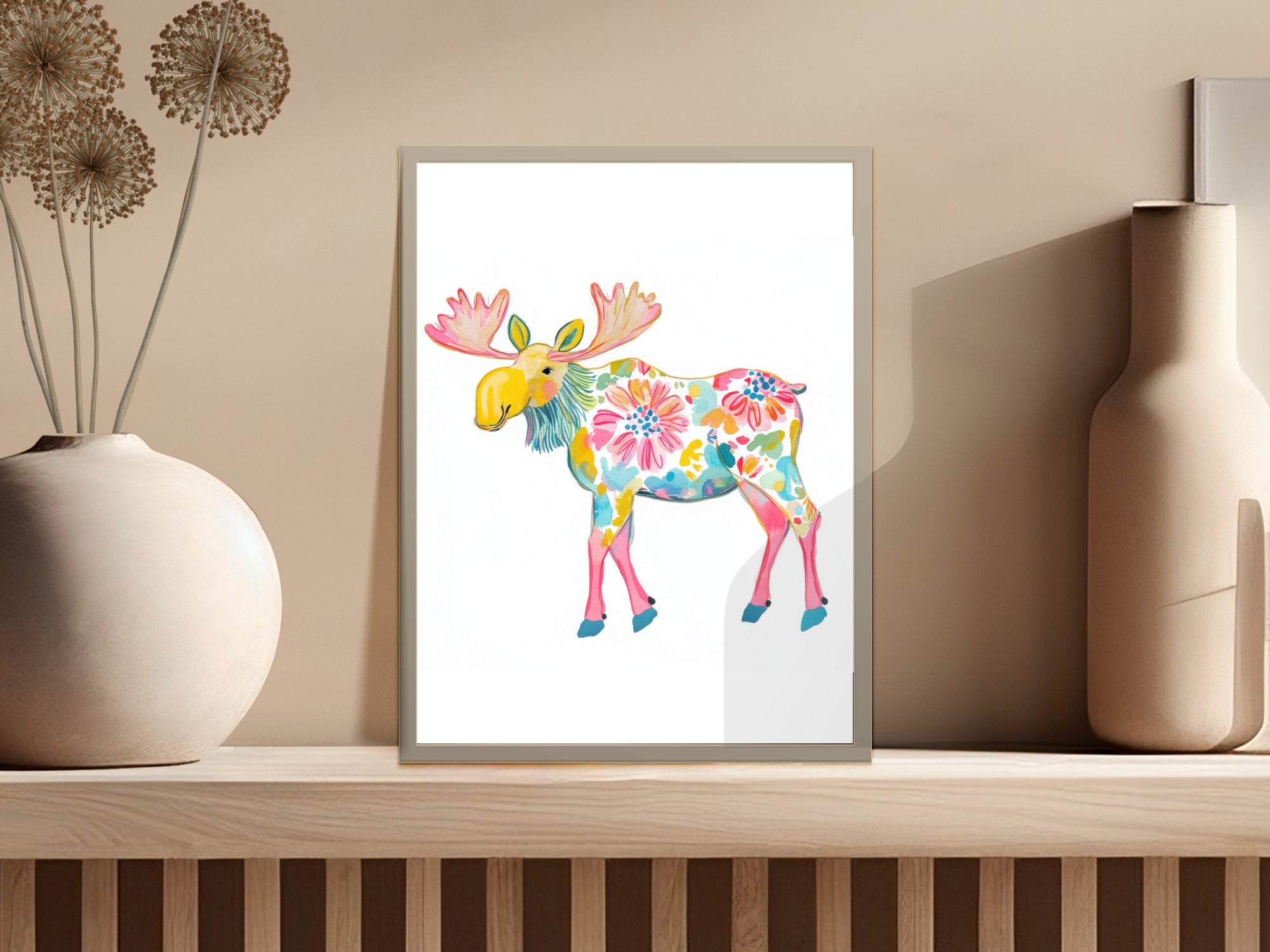 Colorful floral moose artwork in a frame on a shelf.