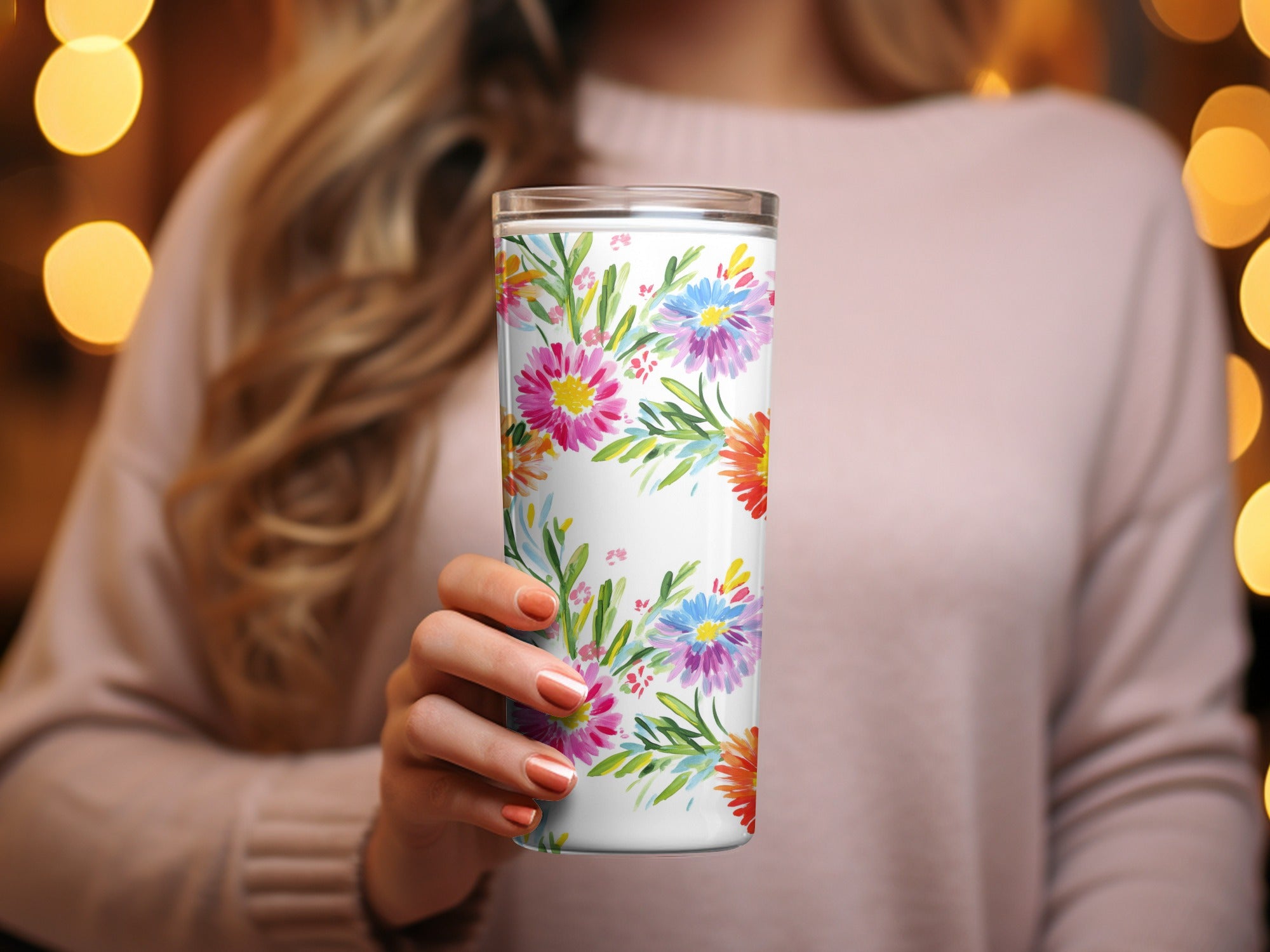 Woman holding a white tumbler with a colorful floral pattern.