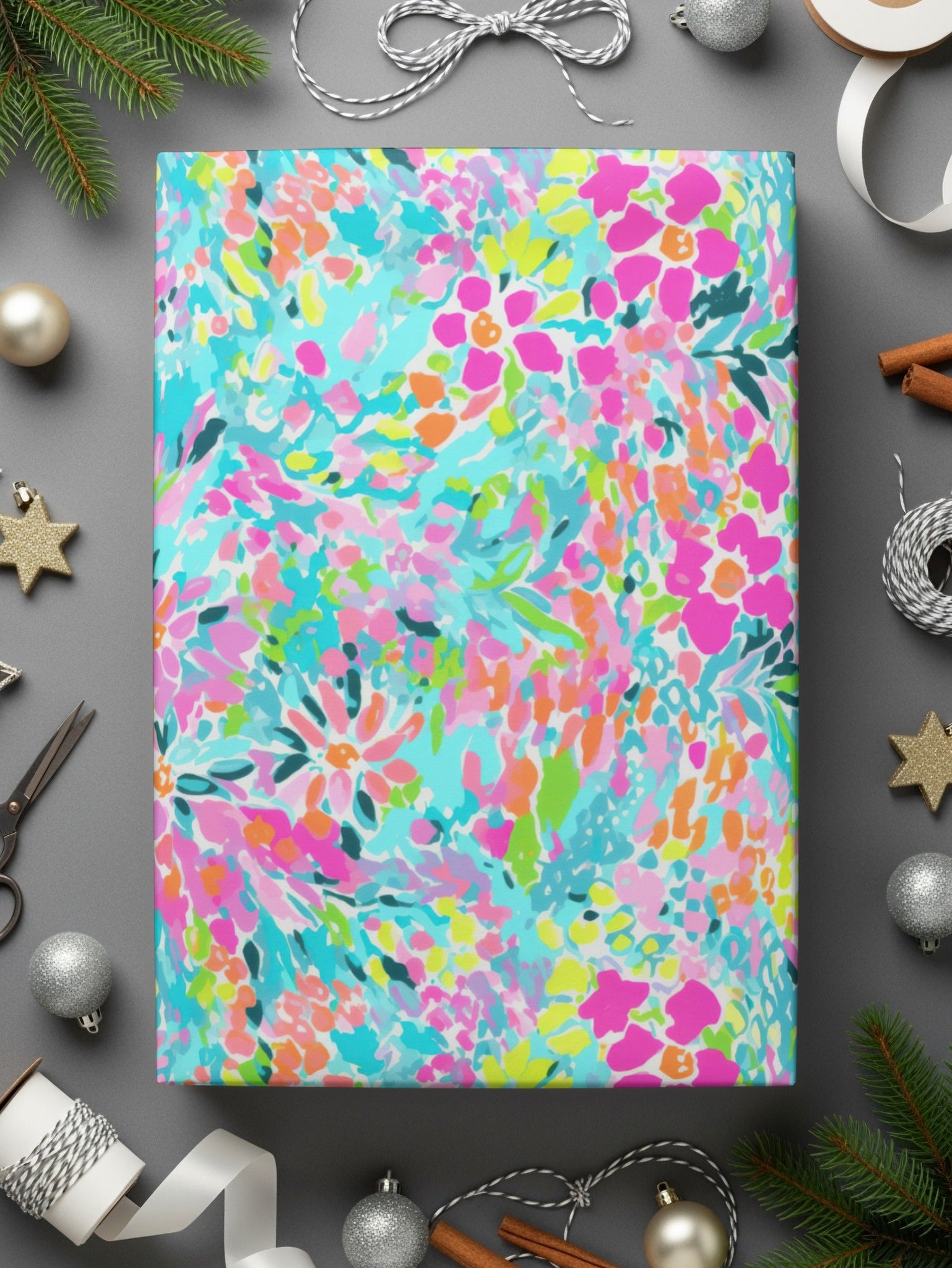 Colorful floral wrapping paper with silver scissors and ornaments on gray.