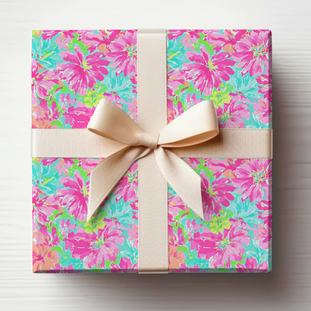 Wrapped gift with pink, teal, and yellow floral pattern and beige ribbon.