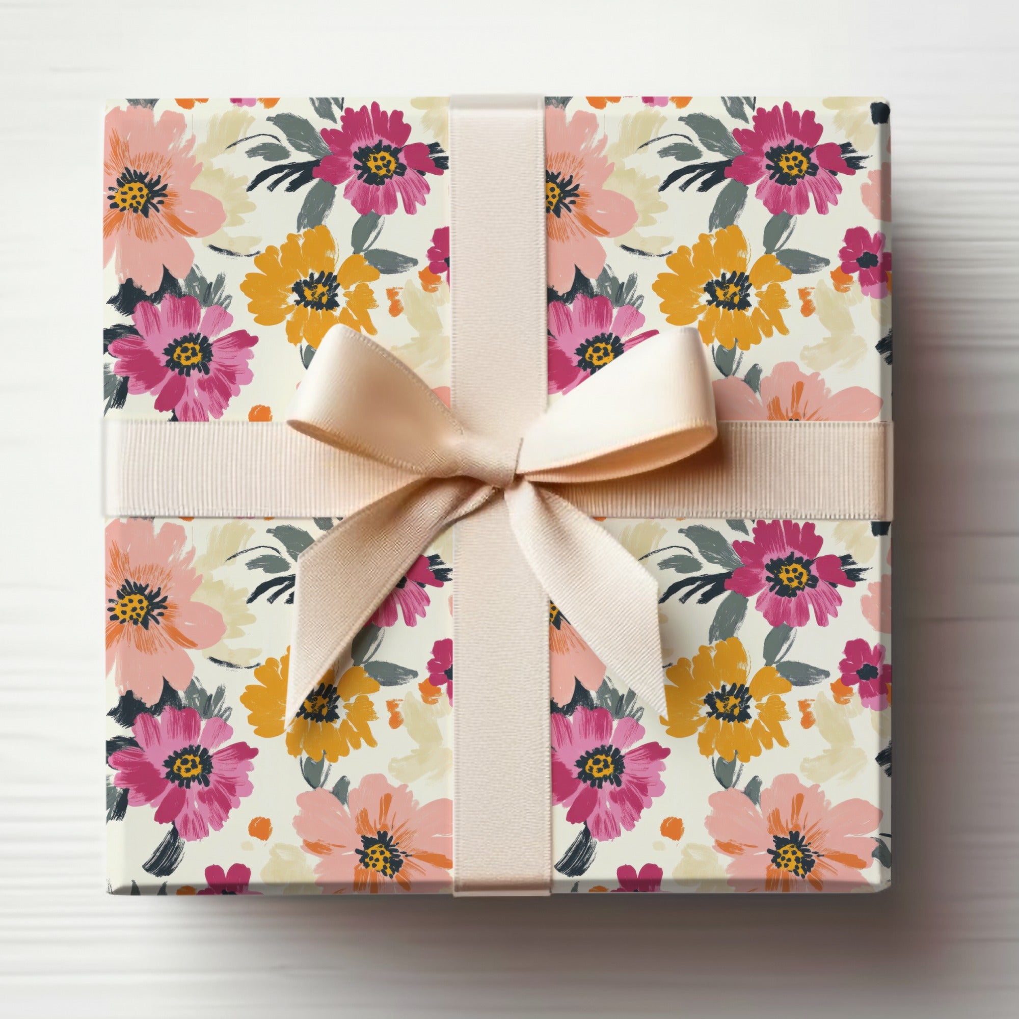 Gift-wrapped box with a pink and yellow floral pattern and a beige ribbon.