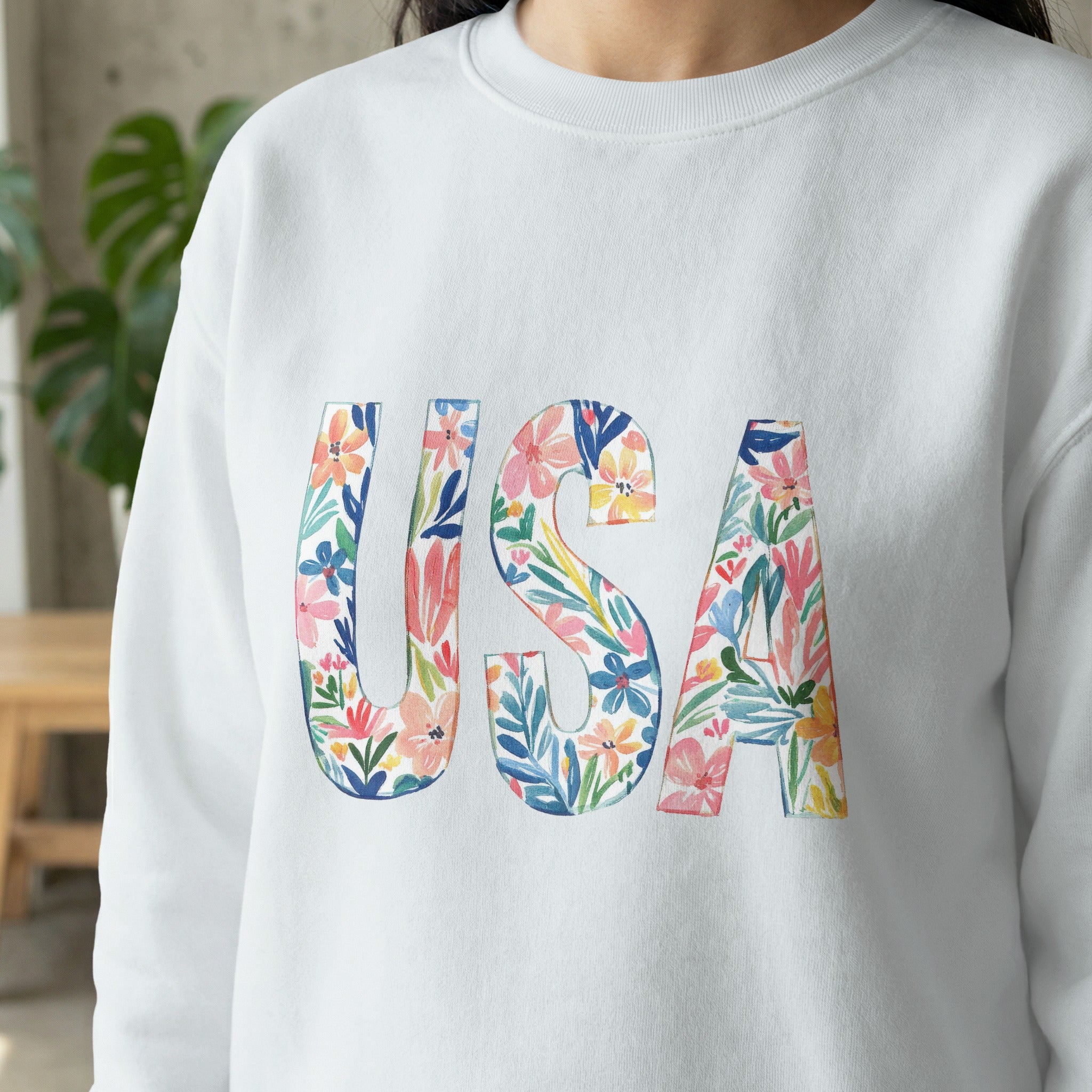 White sweatshirt with "USA" in colorful floral watercolor letters.