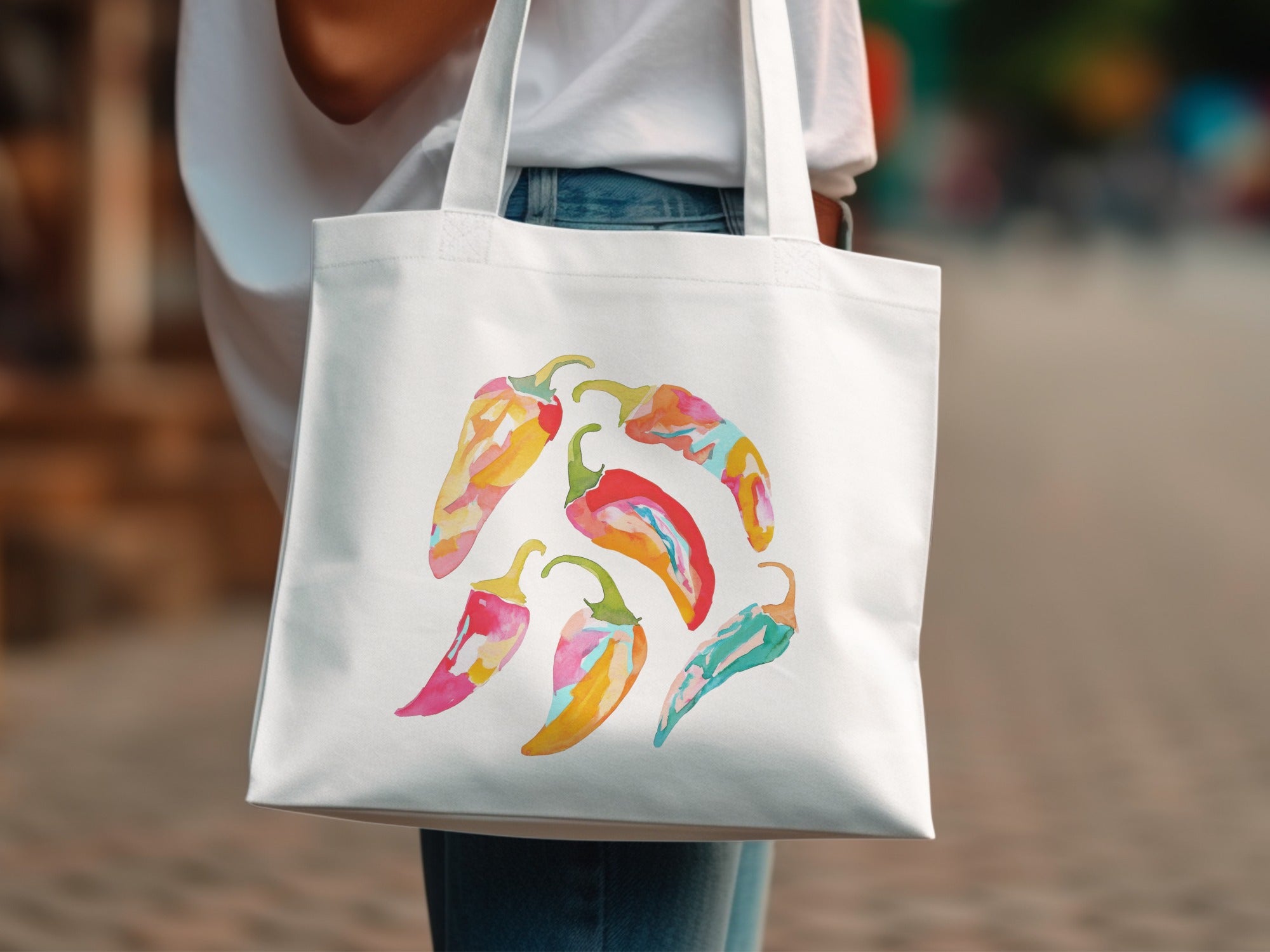 White tote bag with colorful watercolor chili peppers illustration.