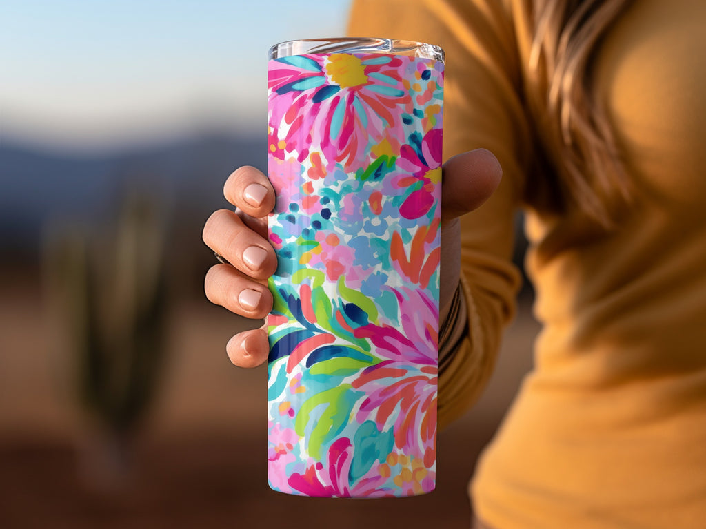 Hand holding a tumbler with a vibrant floral abstract pattern.