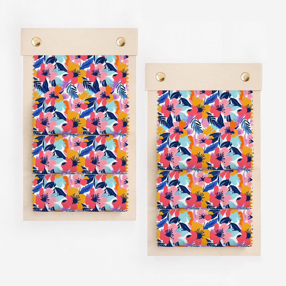 Two fabric swatches with a vibrant floral pattern of pink, blue, and yellow flowers.