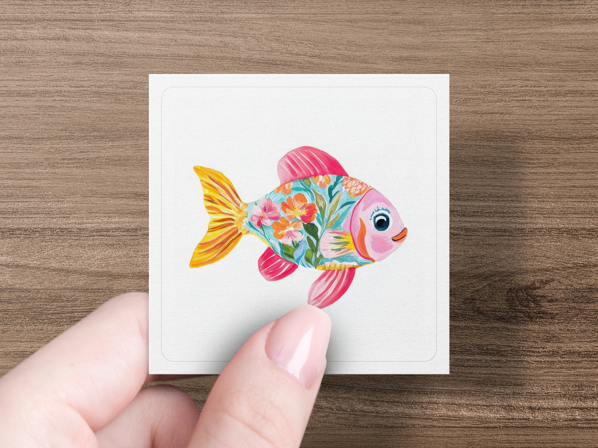 Pink and orange stylized fish illustration with floral pattern on white card.