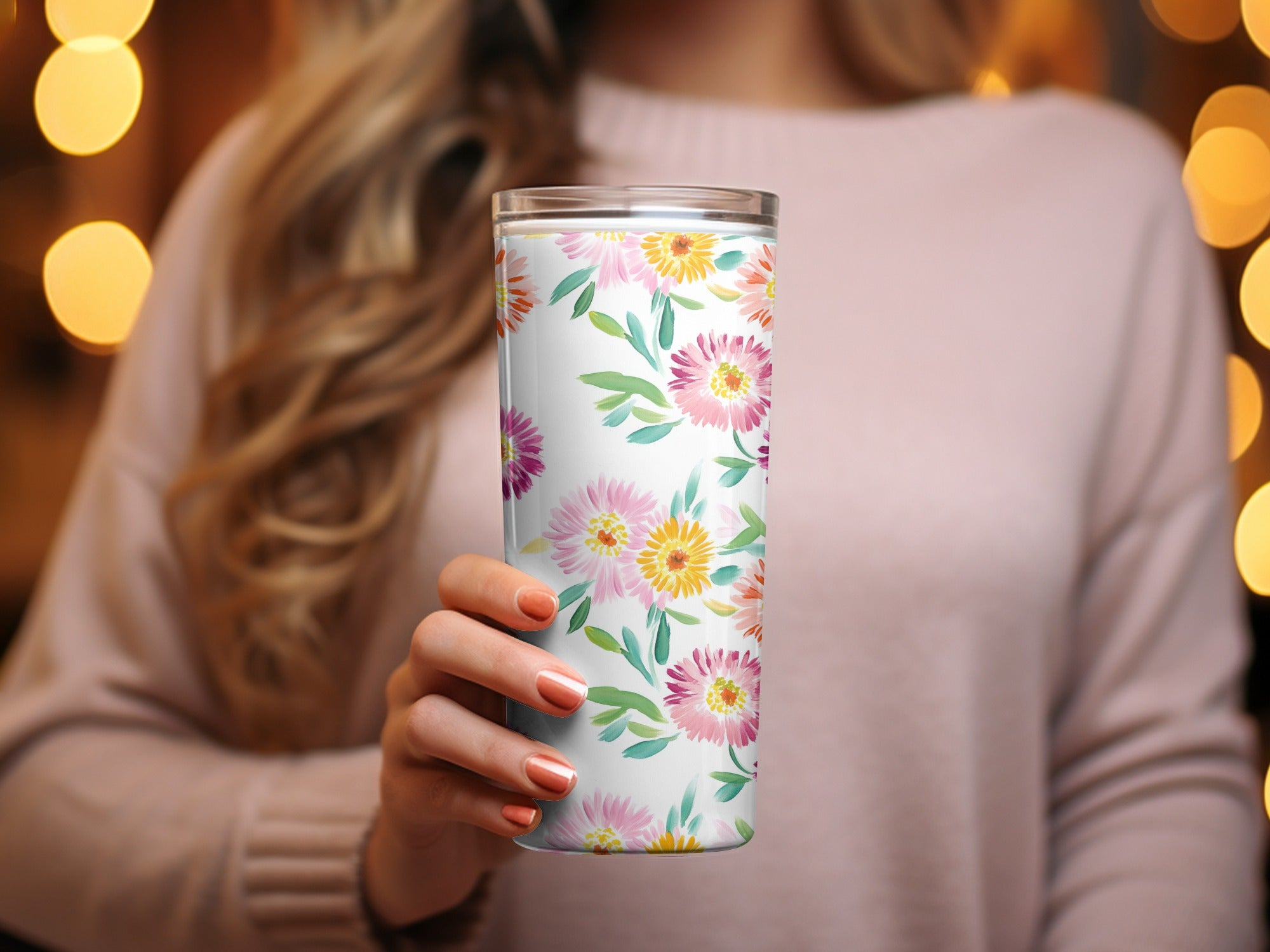 Tall white tumbler with colorful floral pattern held by a woman.