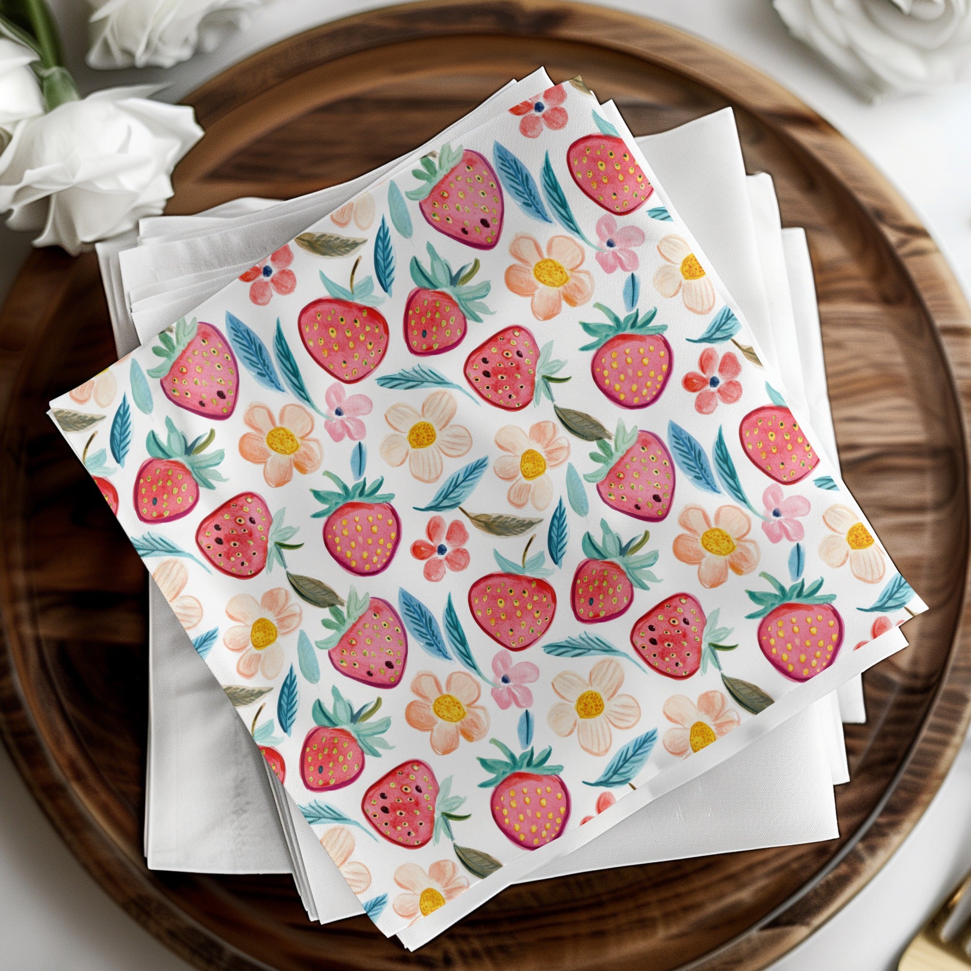 Napkins with a strawberry and floral pattern on a wooden tray.