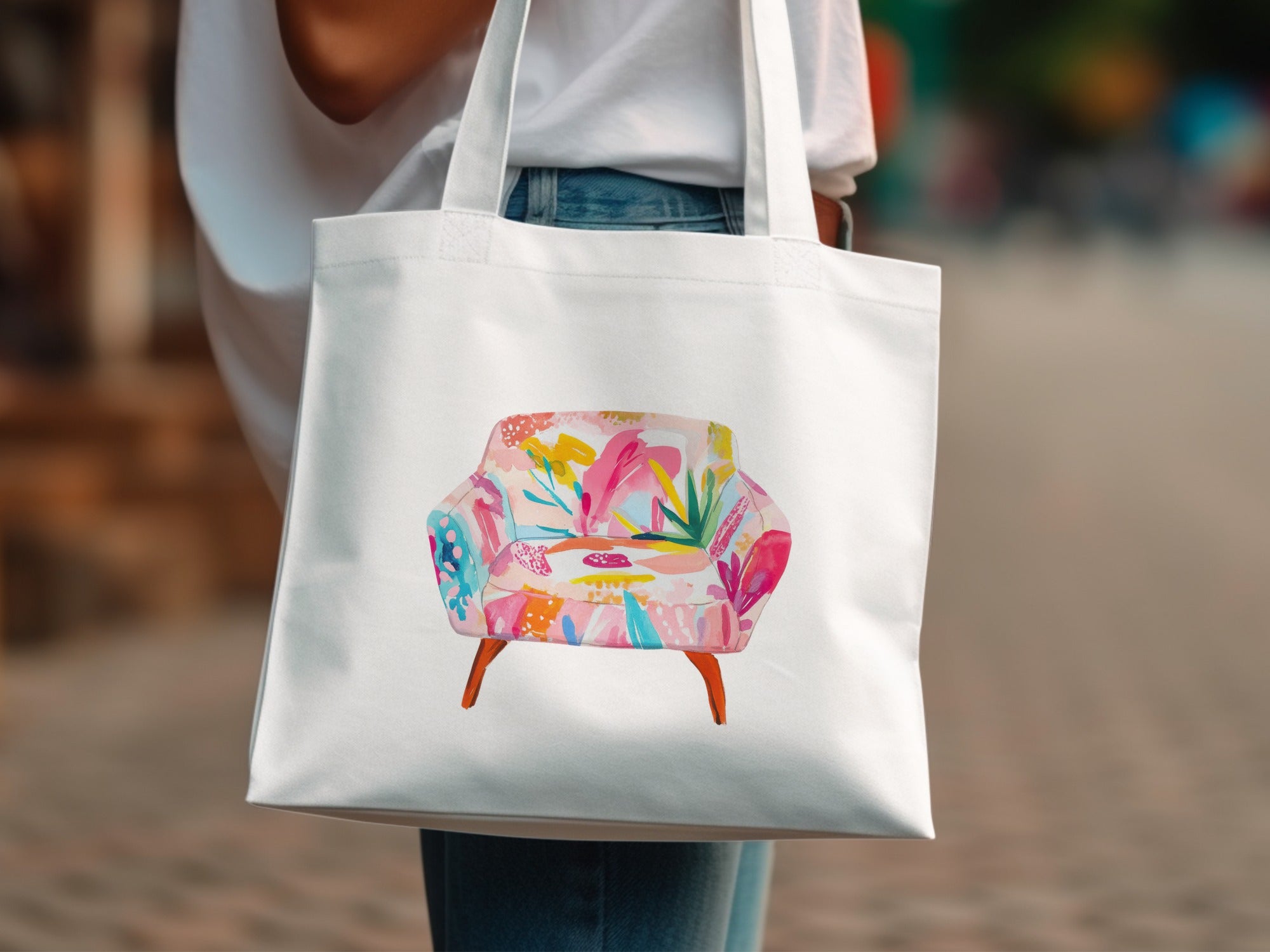 White tote bag with a colorful armchair illustration.
