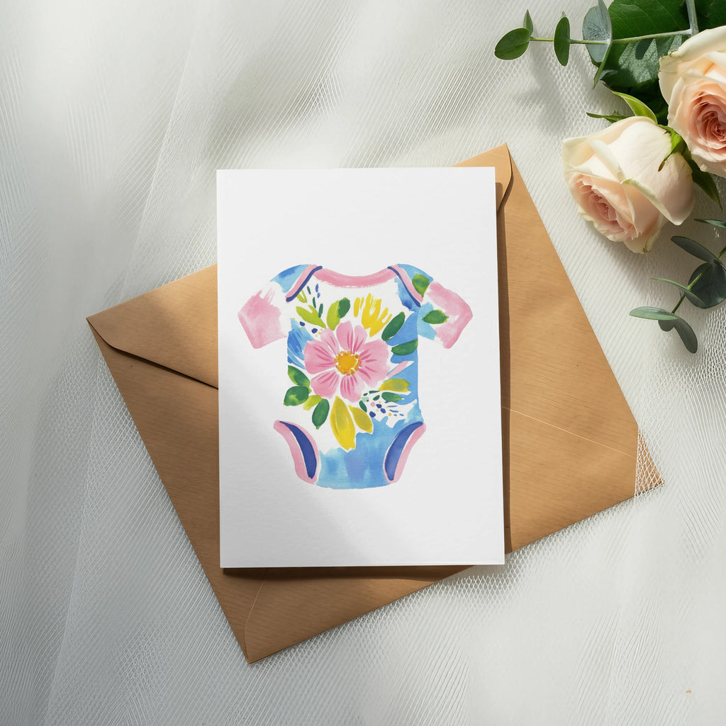 White baby onesie with pink, yellow, and blue floral design on brown envelope.