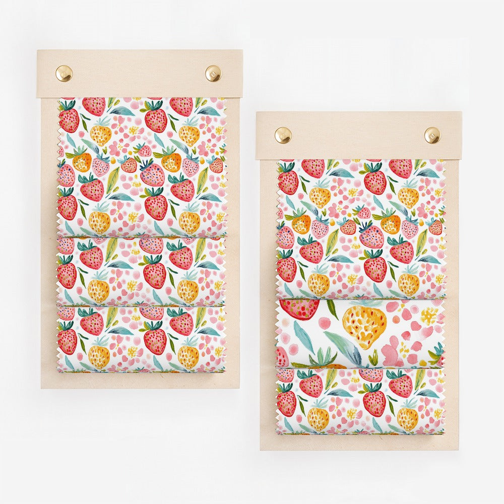Four swatches of fabric with a strawberry pattern arranged on wooden boards.