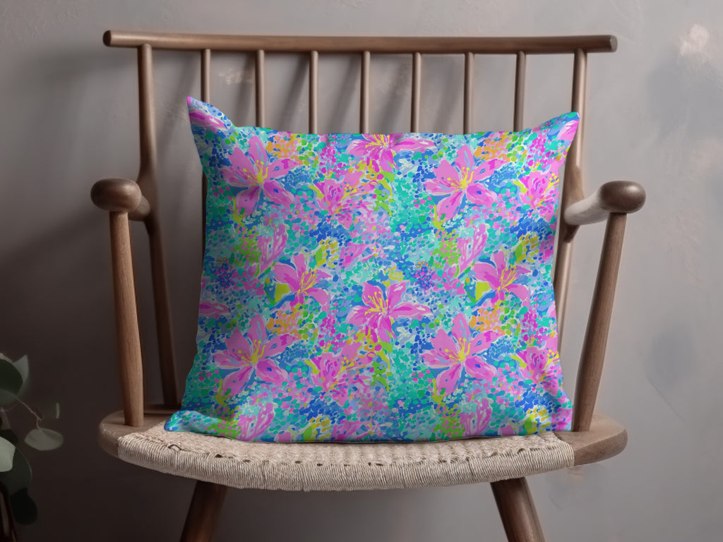 Pink and blue floral print pillow on a wooden chair.