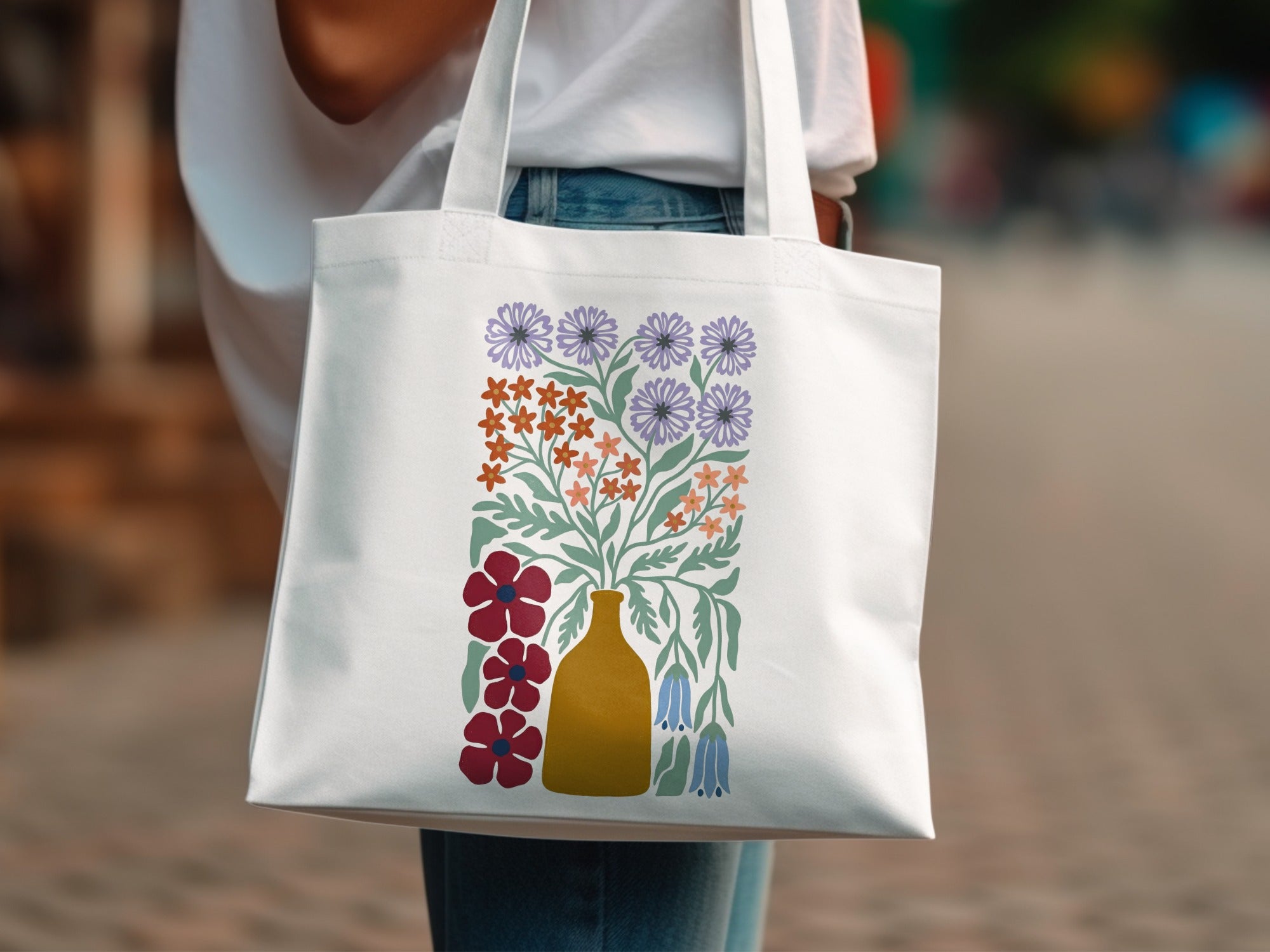 White tote bag with yellow vase and colorful floral illustration.